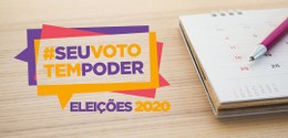 à direita, um calendário de mesa e uma caneta. à esquerda a logomarca das Eleições 2020, na qual...